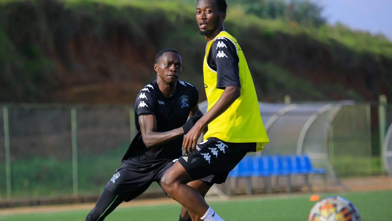Two footballers competing for the ball on a training pitch