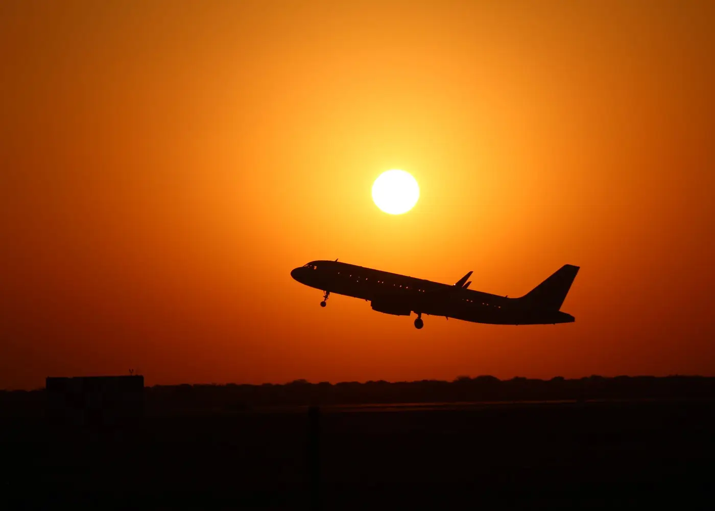 Passenger plane taking off at sunset